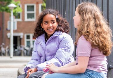 twee leerlingen praten met elkaar op het schoolplein